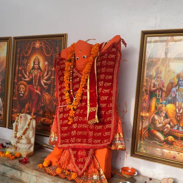 Hanuman ji at the centre of the altar between Durga and the Ram Darbar, marble Ganesha at his feet, loose marigolds and a conch on the ledge.